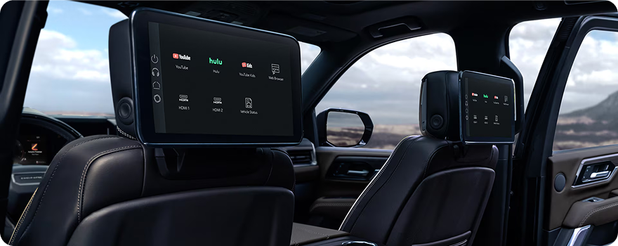 Rear-seat media screens mounted on the GMC Yukon front seatbacks showing streaming apps