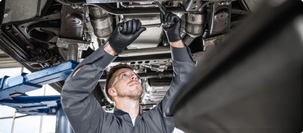 A technician checking transmission fluid beneath a raised vehicle